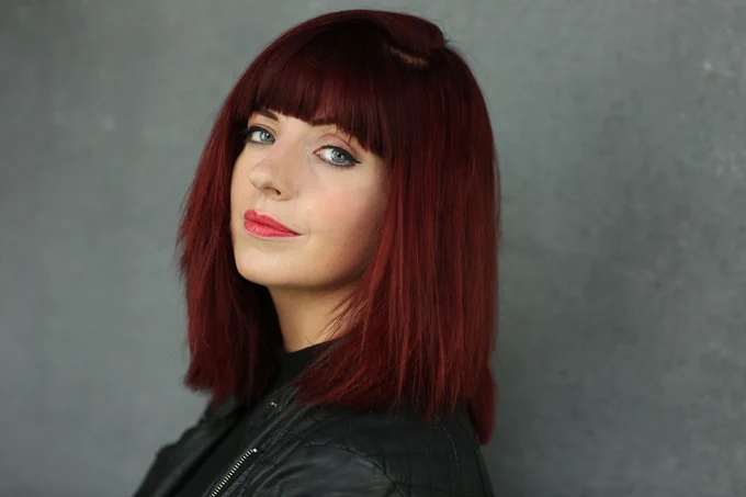 A photo showing a woman posing for a headshot against a grey background