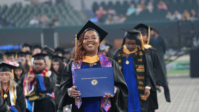 student holding diploma smiling at camera
