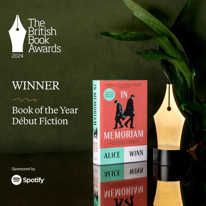 In Memoriam stood upright on a mirrored table next to the golden Nibbie trophy in front of a plant, in white text reads: winner, Book of the Year Debut Fiction