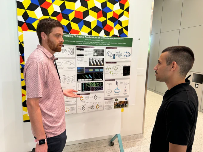 Two people talking in front of poster