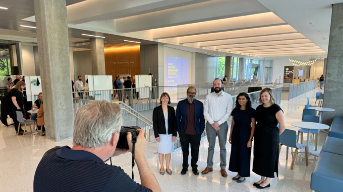Group of five people standing in lobby with photographer in foreground