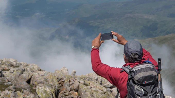 A person taking a photo of a misty landscape, using a smartphone.