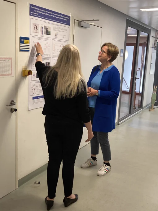 Photo of two talking women standing in front of a scientific poster. On the left is MDC group leader and organoid researcher Mina Gouti; on the right is politician Gabriele Bischoff, a member of the European Parliament. © Jutta Kramm, Max Delbrück Center