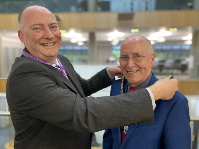 Outgoing Chair Cllr Roger Dicker hands over the chains of office to newly elected Chair Cllr Pat Hanlon.