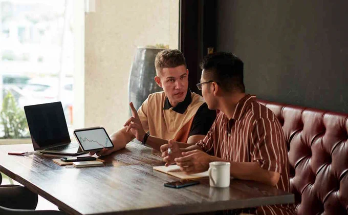 Image d'illustration montrant deux personnes négociant à une table de café