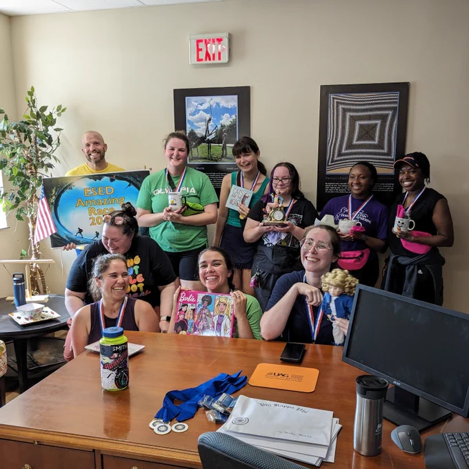 A group of people wearing medals and holding up their various prizes, all smiling and laughing.