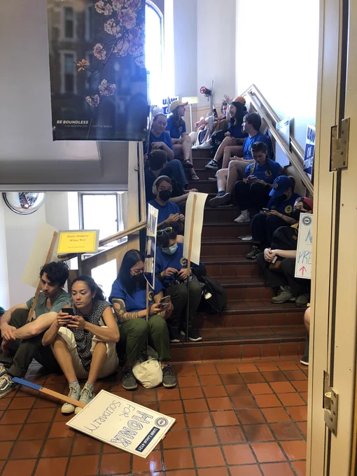 About 15 UAW members with picket signs sitting along a stairwell