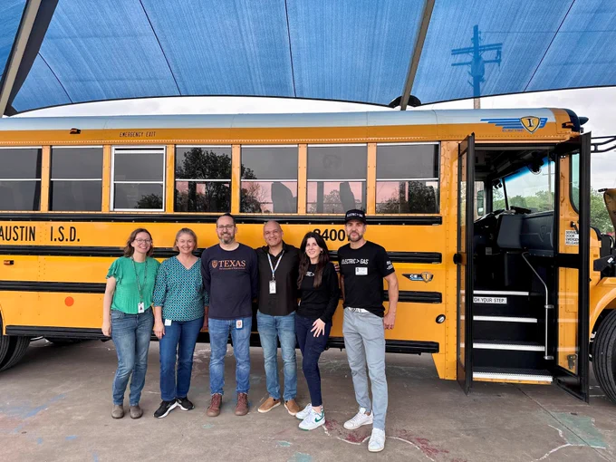 Image of Austin Energy, Austin ISD and partnering organizations pose for a photo in front of an electric school bus.