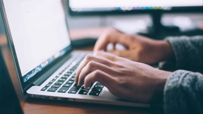 Stock image of a man typing on a laptop