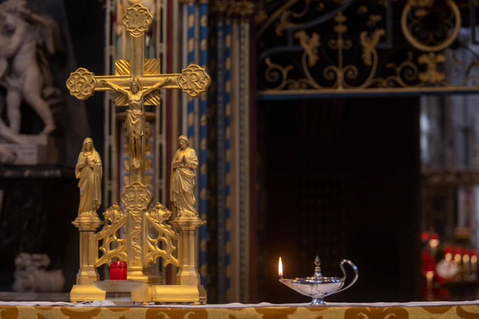 The nave altar in Westminster Abbey, with a gold coloured crucifix and a lit lamp, symbolising Florence Nightingale 