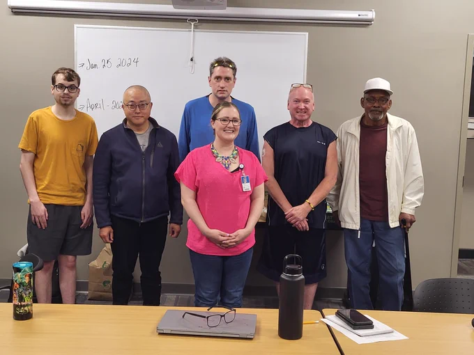 A group of individuals from IowaWORKS and Iowa Vocational Rehabilitation pose for a photo behind a representative from UnityPoint Health.