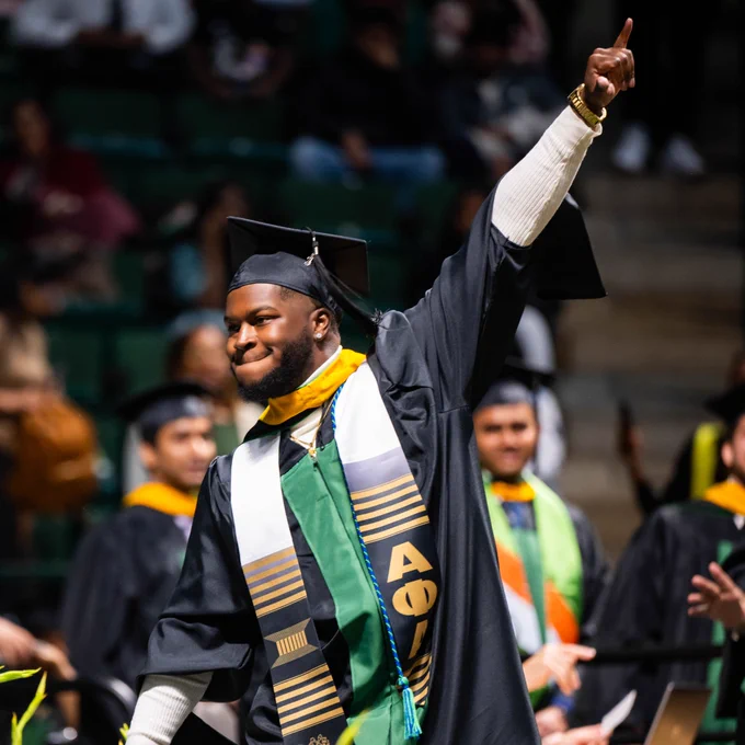 A master's student celebrates as they cross the stage to receive their degree.
