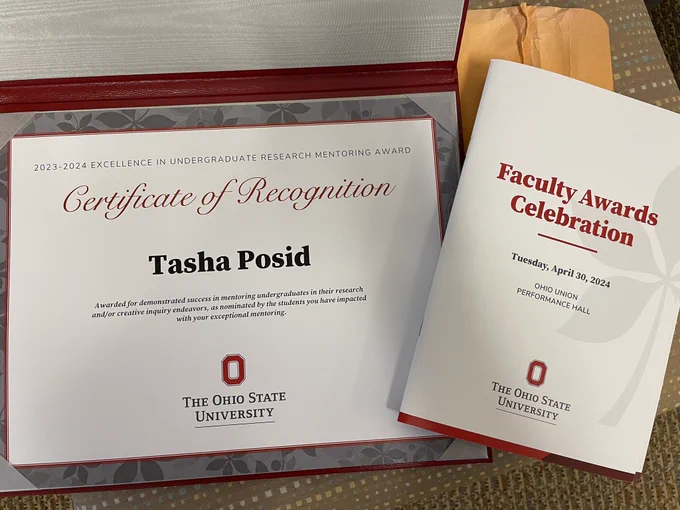 Certificate of recognition for Tasha Posid alongside a booklet from the awards celebration.