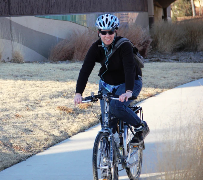 Person wearing a helmet, biking along a trail.