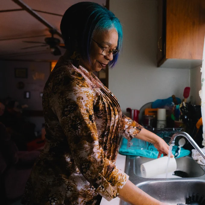 Portrait of Donna washing dishes at her sink.