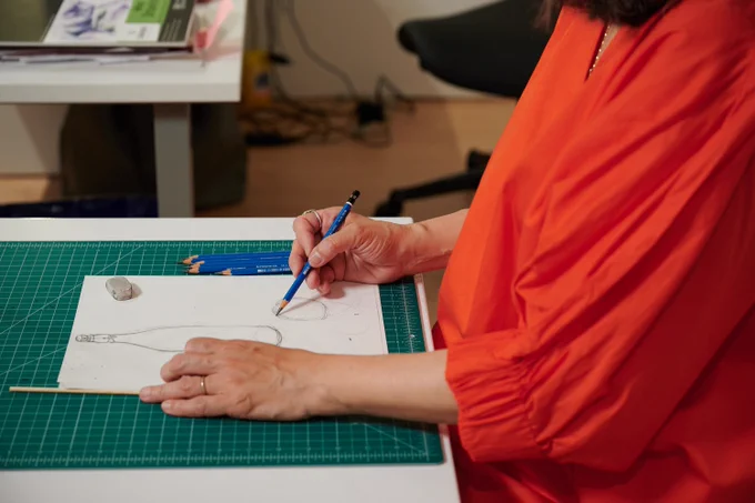 Close-up of a person in an orange shirt drawing with her right hand