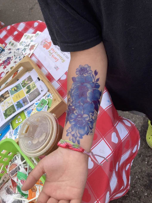A large blue flower temporary tattoo on a child's arm.