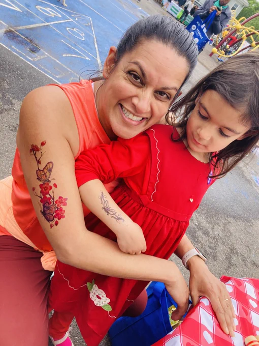 An adult and child show off their colorful temporary tattoos.