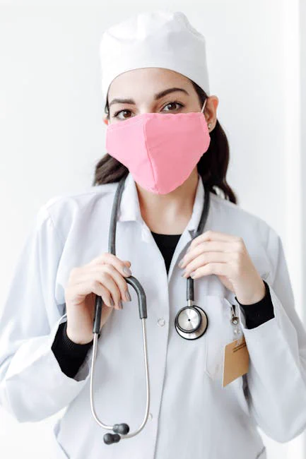 A Doctor with Stethoscope Wearing Pink Face Mask while Looking at the Camera