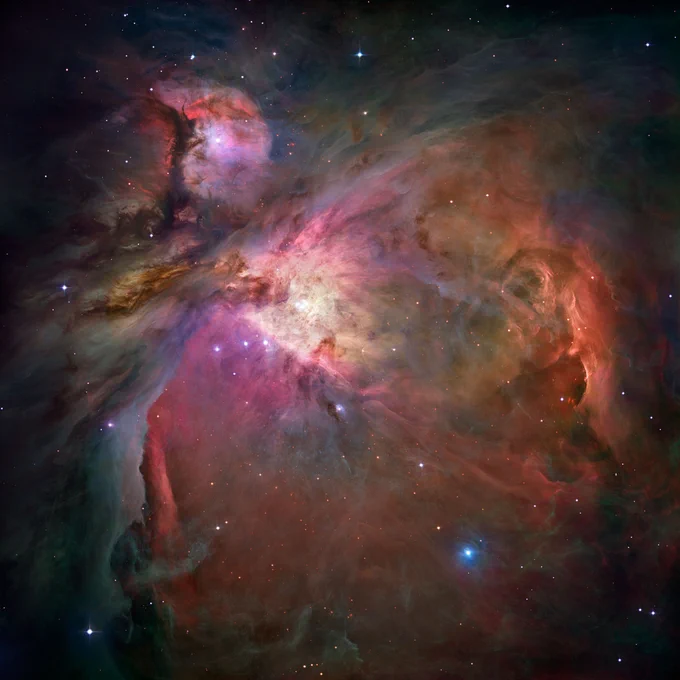 Orion Nebula. Vibrant clouds of orange, purple, pink, gray-green and yellow shine against a black, star-speckled background. The colors are arranged in roughly two connected sections: a smaller, roughly crescent-like piece in the upper left corner, and a larger fan-shaped portion that extends from the bottom of the crescent to the bottom lower right. Several stars shine throughout and around the nebula.