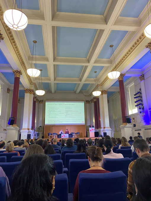 Photo of a presentation from MSF Scientific days with Dr. Ahmed Fahal speaking at a podium in front of an audience, with slides from his presentation on mycetoma in the background.