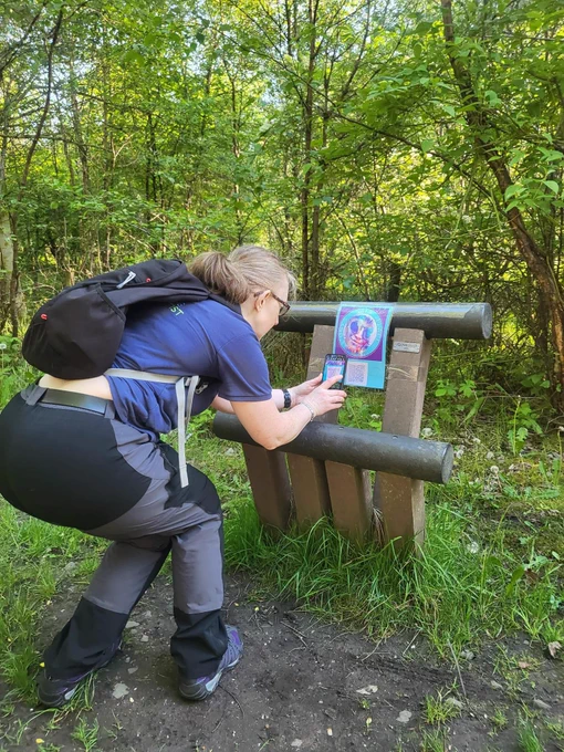 An individual bending over to scan a QR code on a poster