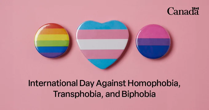 A group of buttons in the colours of the pride, transgender pride and bisexual pride flags on a pink background. The text reads “International Day Against Homophobia, Transphobia, and Biphobia.” 