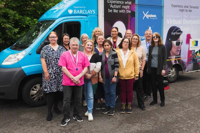 A group of staff standing in front of the virtual dementia bus. 
