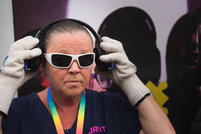 A women wearing glasses and headphones to help her understand what it may be like to live with dementia. 