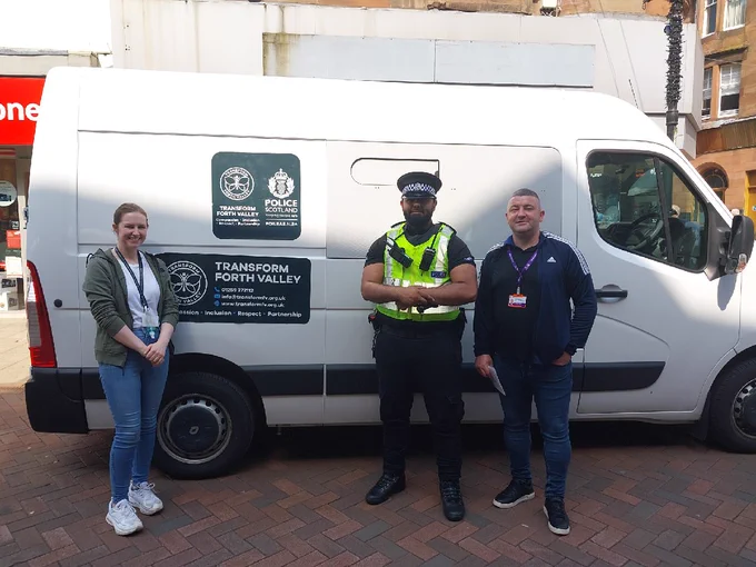 Drugs addiction services partners and a police officer in uniform standing in front of a white van on Falkirk high street