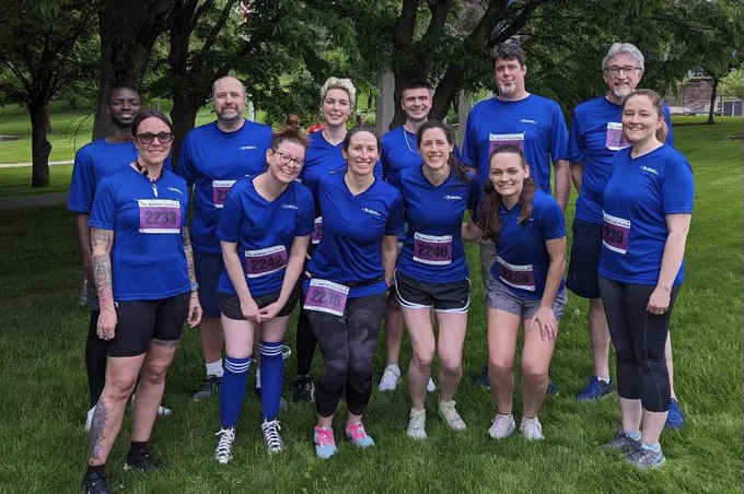Group picture of EFC employees wearing blue shirts and running bibs outside
