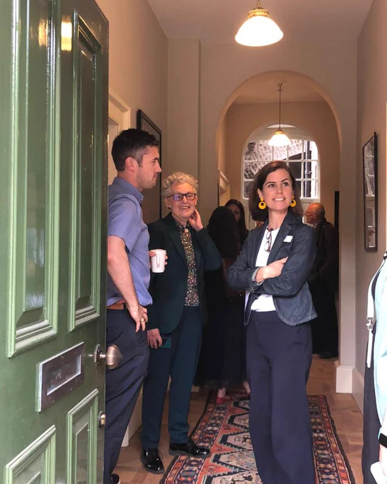 A group of people standing in a hallway next to an open green door