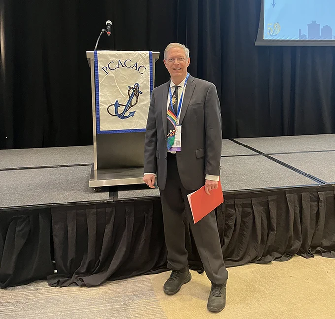 Kevin Terry posing next to a podium that reads PCACAC with a boat anchor