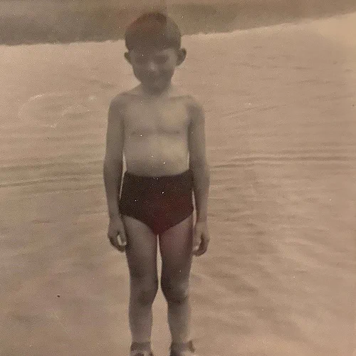 A photograph of a child standing in the sea.
