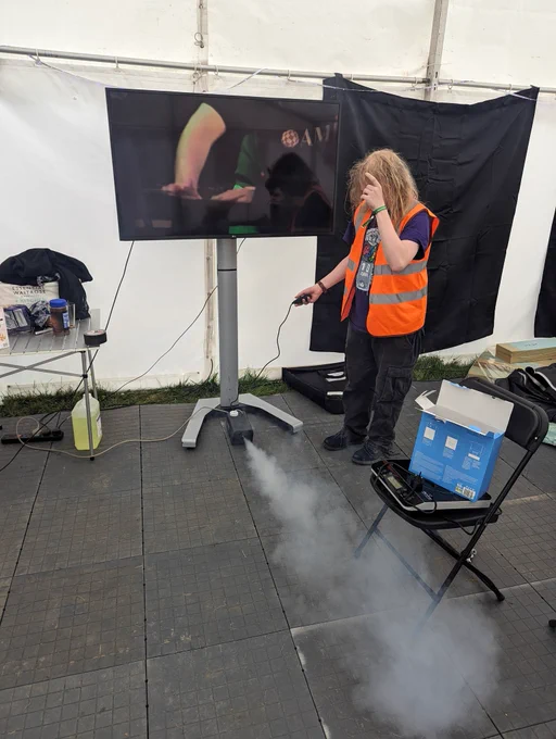 Person holding a tote control to a smoke machine with smoke coming out 