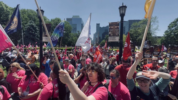 A huge crowd of trade unionists flying union flags on the lawns of Queen's Park.