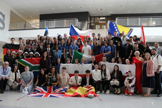 Large group of students and teachers posing with various flags
