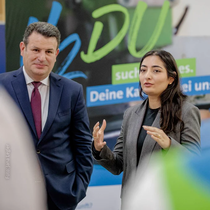Foto von Bundesarbeitsminister Hubertus Heil und Integrationsbeauftragter Reem Alabali-Radovan, die nebeneinander stehen. Frau Reem Alabali-Radovan spricht und benutzt dabei gestikulierend ihre Hände.