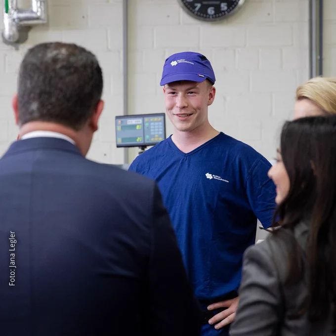 Foto von Bundesarbeitsminister Hubertus Heil und Integrationsbeauftragter Reem Alabali-Radovan, die mit einem Auszubildenden der Berliner Wasserbetriebe sprechen.