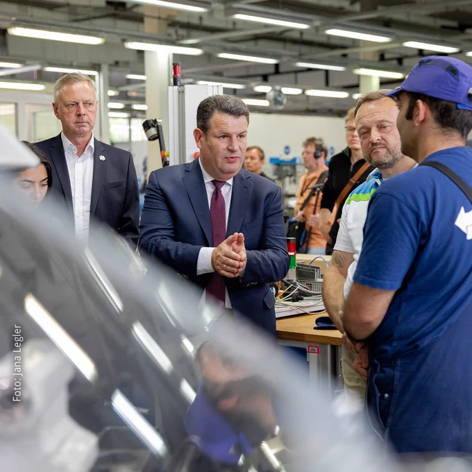 Foto mit Fokus auf Bundesminister Hubertus Heil der mit einem Auszubildenden von den Berliner Wasserbetrieben spricht. Auf dem Foto sind außerdem die Integrationsbeauftragte Reem Alabali-Radovan sowie zwei Mitarbeitende der Berliner Wasserbetriebe zu sehen.