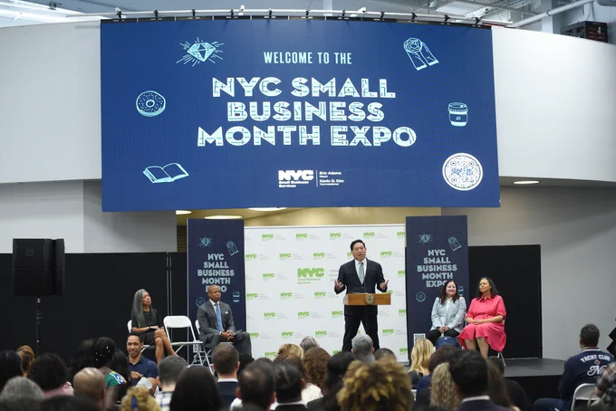 Commissioner Kim addresses crowd with large NYC Small Business Month Expo projection behind him