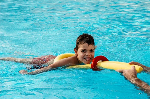 A child being pulled on a floating device in a pool. 