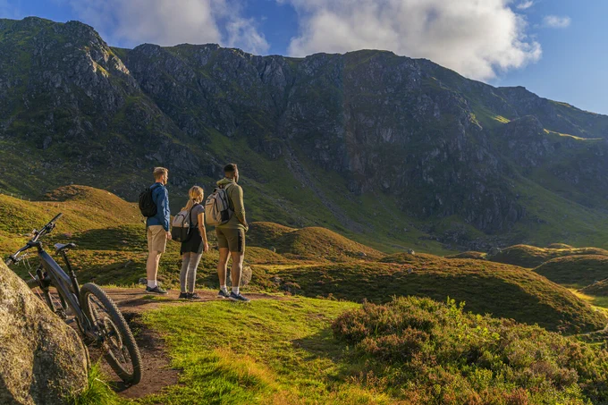 Three cyclists standing next to their bikes and admiring the view over Corrie Fee in the Cairngorms National Park.