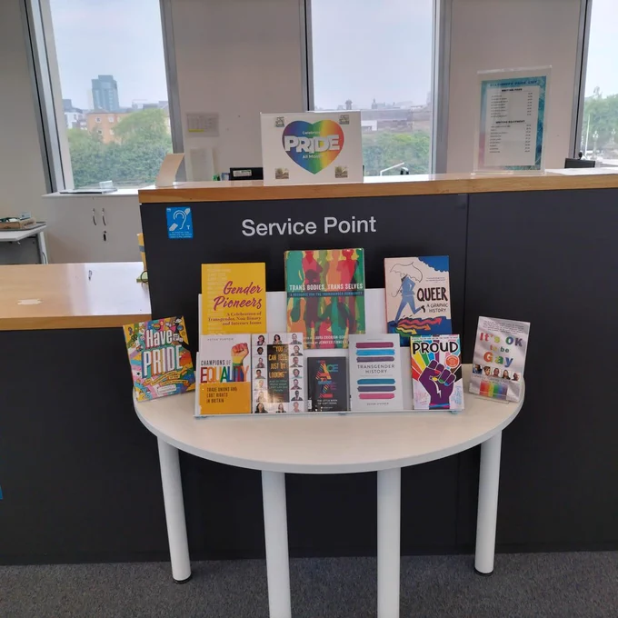 Photograph of a white table at Riverside Library, upon which books are displayed for Pride Month.