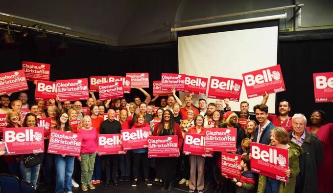 Bell stands in the middle of dozens of Labour members, many of them wearing red. Many hold signs that read 'Bell Ribeiro-Addy' and 'Clapham & Brixton Hill Constituency Labour Party'.