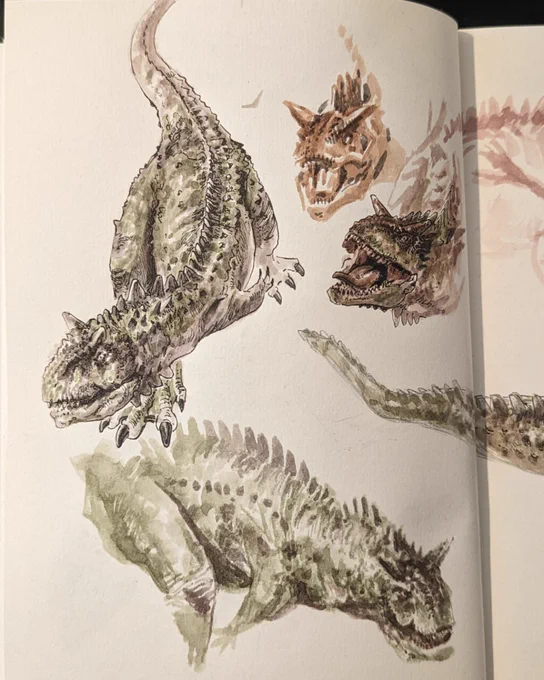 An open sketchbook displaying four detailed illustrations of dinosaur creatures. The creatures vary in posture and features, with scales and distinct facial expressions, shown in muted earth tones. 