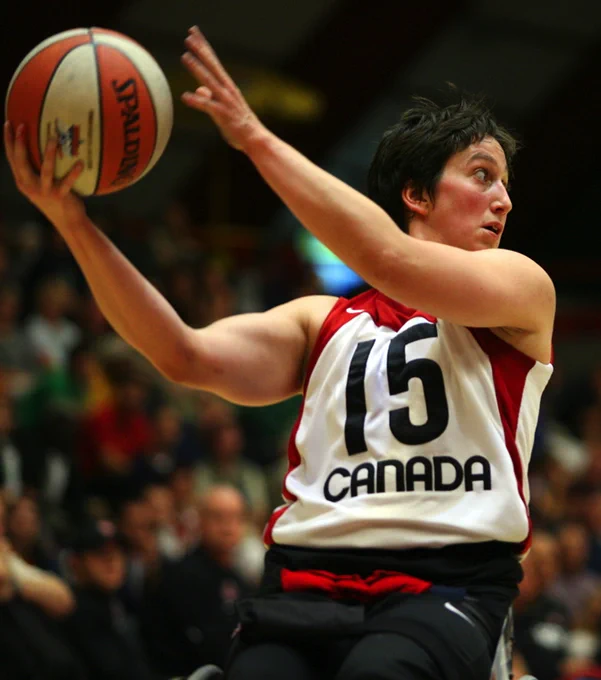 Action shot of Danielle Peers holding a basketball as they compete with the Canadian wheelchair basketball team.