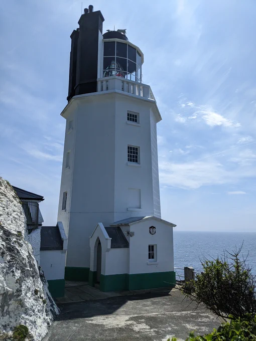 The white tower of a lighthouse with the blue sea and sky in the background