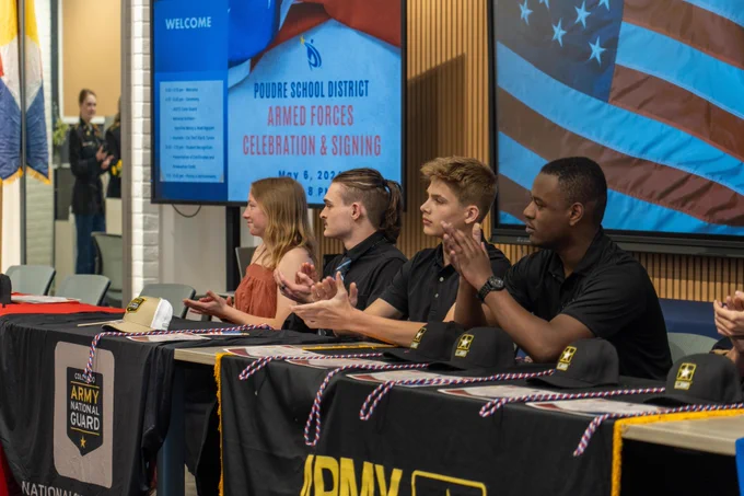 Students sit behind tables listed with the different branches of the military as they applaud for other students being recognized at the P S D Armed Forces Day Celebration & Signing.
