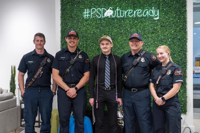 A student smiles for a photo with a group of people in front of a sign that says # P S D Future Ready after the P S D Armed Forces Day Celebration & Signing.